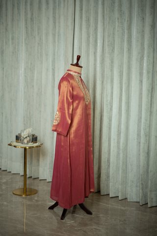 side view of maroon silk kurta with intricate gold embroidery on the neckline and sleeves, displayed on a mannequin against a soft green curtain backdrop.