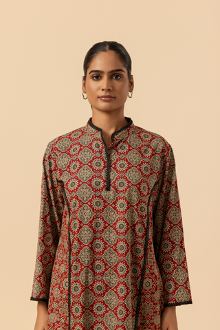 Closeup view of a model featuring a red patterned ajrakh print farshi salwar & kurta, set against a soft beige background.