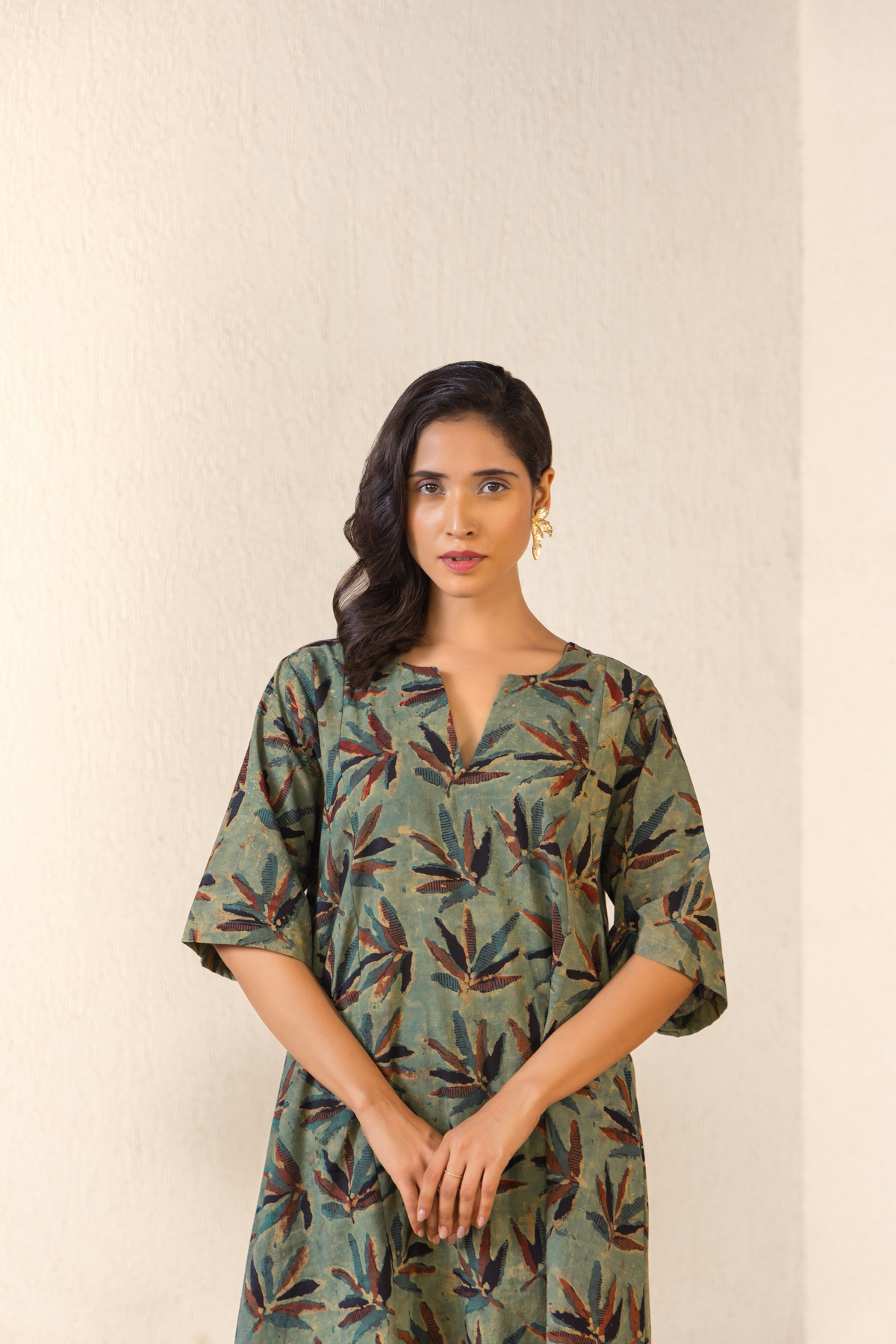 Closeup View of a woman dressed in a green botanical print linen kurta set with matching pants, styled in a minimalist outdoor archway setting.