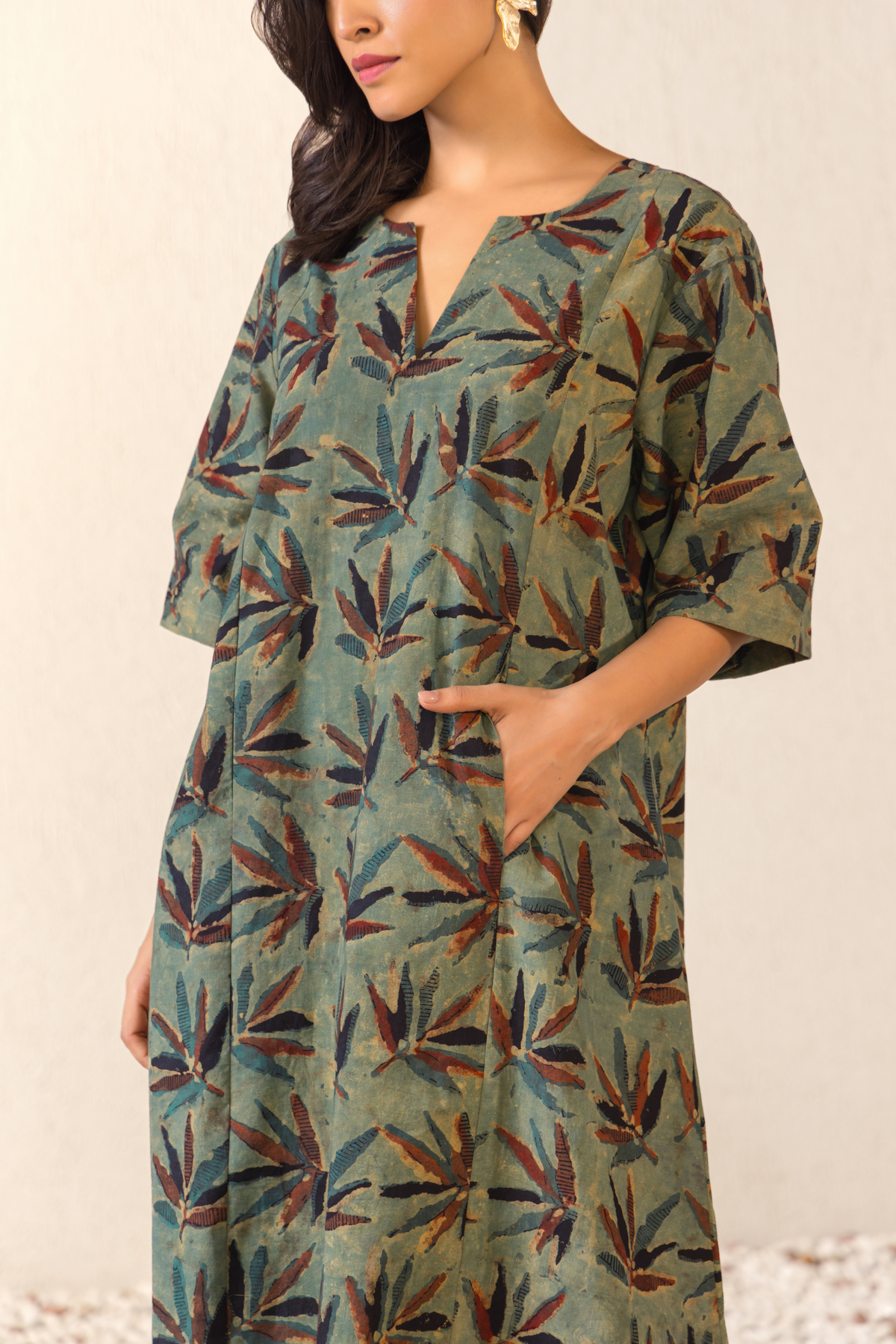 Closeup View of a woman wearing a green botanical print linen kurta set with matching pants, styled in a minimalist outdoor archway setting.