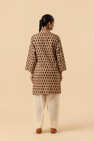 Back view of a person wearing a traditional brown patterned chikan farshi salwar co-ord set with white embroidered pants and brown sandals, set against a neutral background.