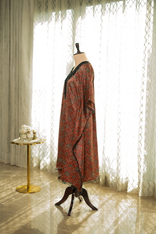 Side view of red and black printed kaftan with intricate detailing, displayed on a mannequin. Features a relaxed fit and delicate tassel accents
