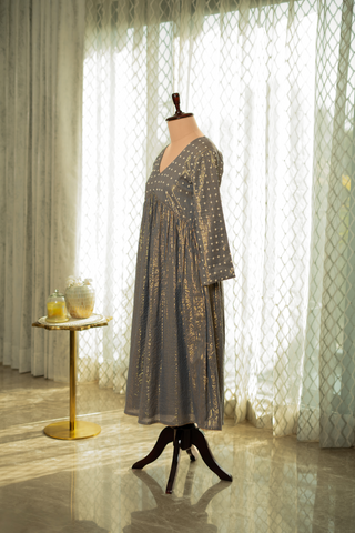 Left side view of a stylish grey anarkali kurta set, paired with a black polka-dot dupatta, displayed against a sunlit.