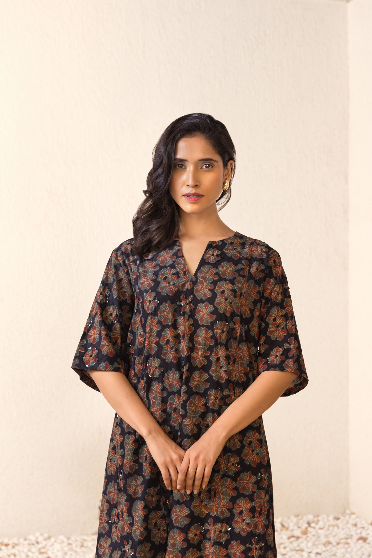 Woman wearing a black floral printed co-ord set with a V-neck and wide sleeves, styled with minimal accessories against a neutral background.