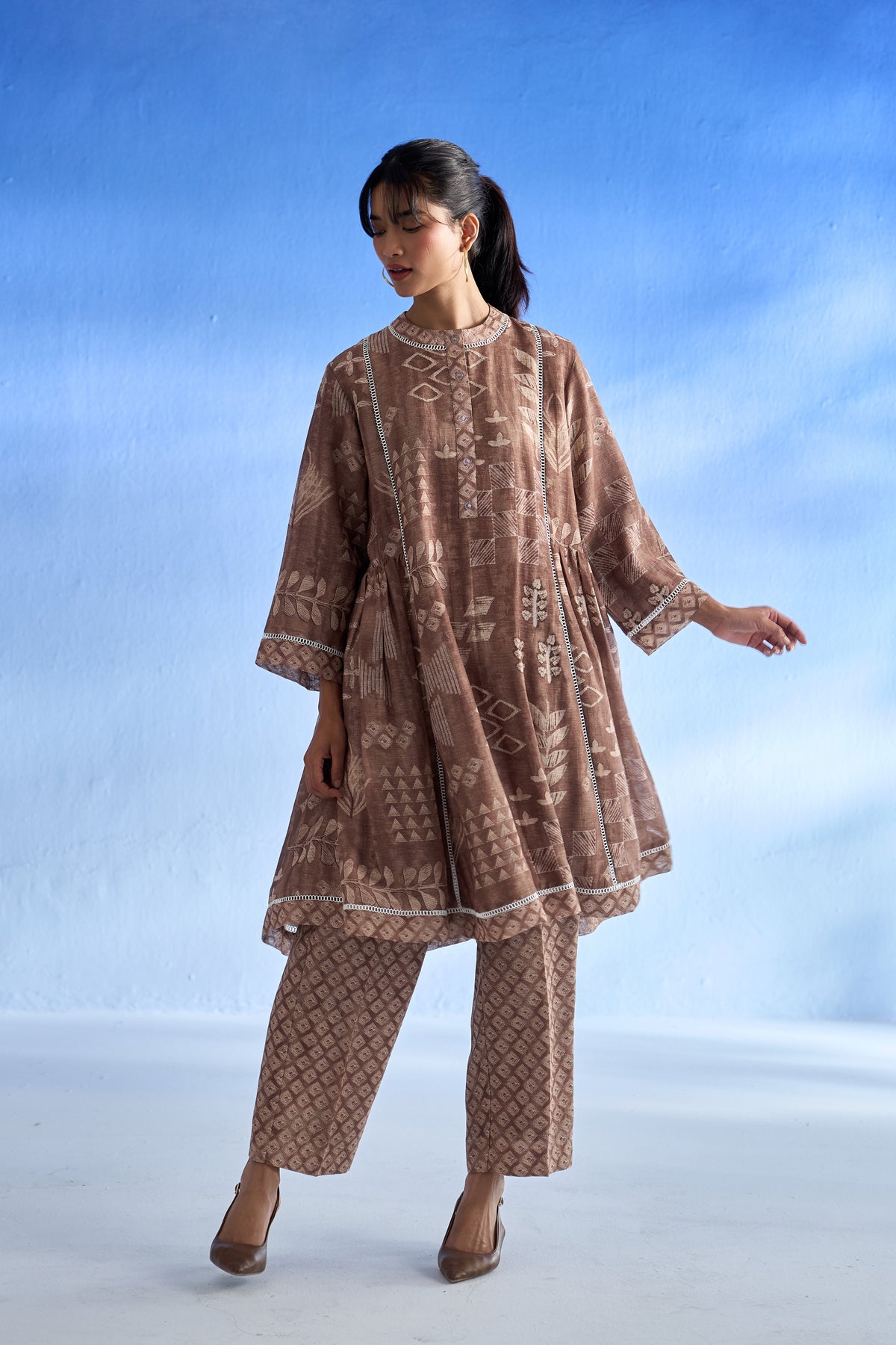 Woman wearing a brown patterned linen co-ord set against a blue sky background